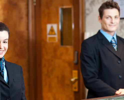 Two hotel staff members standing behind the front desk.