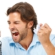 Man sitting at a desk looking frustrated at an old desk phone