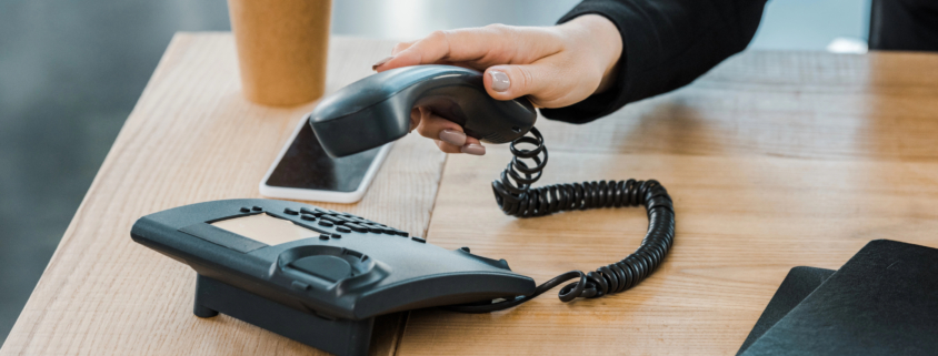 Woman sitting at a desk putting the desk phone down after a call