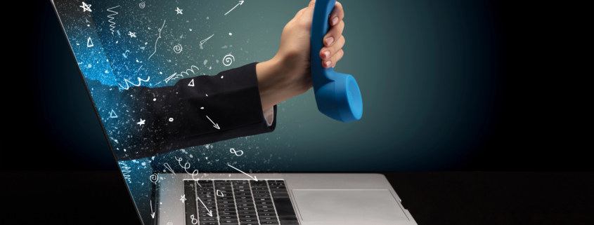 Hand holding a telephone receiver emerging from a laptop screen